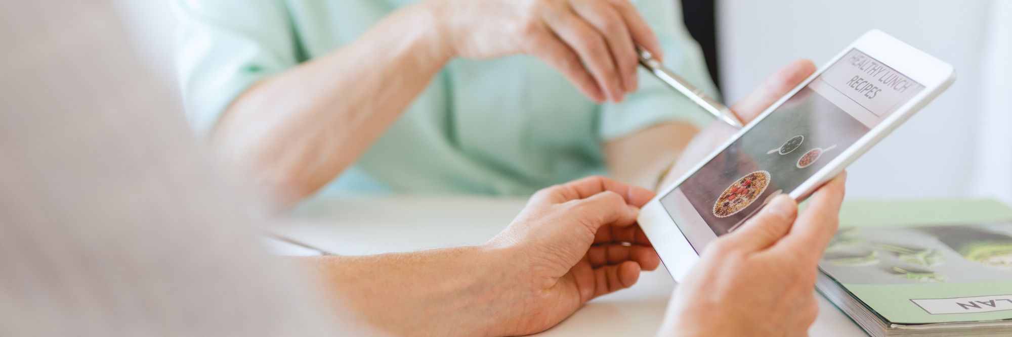 Older nutritionist planning the meals for patient with a tablet application