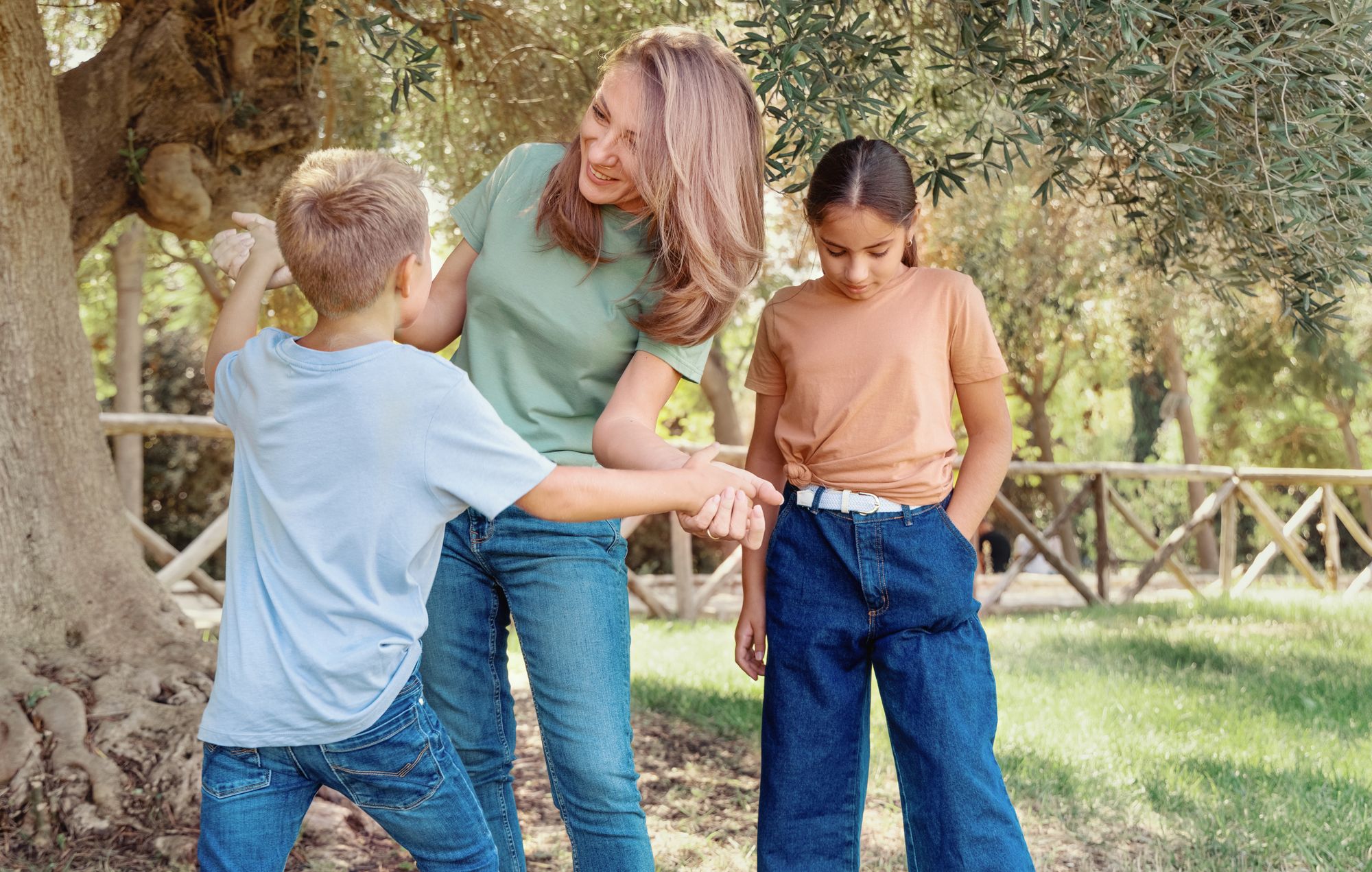 Cute kids and woman having fun in a park in summer.