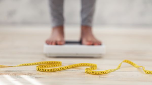 lady standing on scales, checking her weight, focus on measuring tape